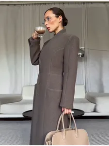Detail of elegant taupe long coat featuring shoulder pads and cinched waist design