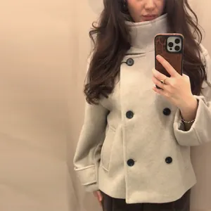 Woman wearing beige short double-breasted wool coat with stand collar for commuters