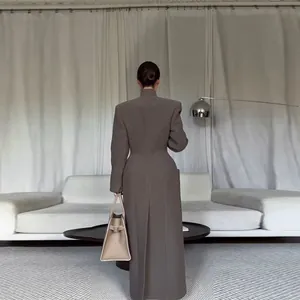 Back view of an elegant long tailored coat with padded shoulders and cinched waist.