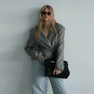 Detailansicht eines grauen Blazers mit schwarzer Handtasche und hellblauen Jeans