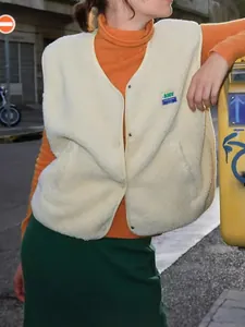 Gros plan détaillé d'un gilet sans manches en polaire blanc crème avec écusson et texture