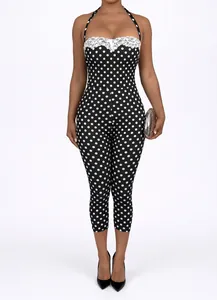 Detail of polka dot halter jumpsuit with white lace trim and slim fit design.