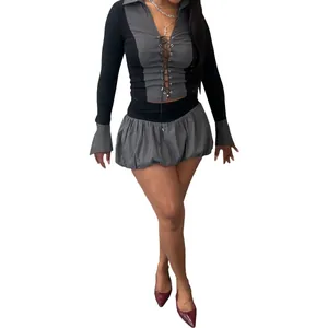Nahaufnahme eines zweiteiligen grau-schwarzen Schnüroberteils und Faltenrock-Shorts-Sets.