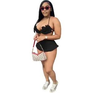 Fashionable woman in black ruffled halter top and matching shorts set posing with handbag