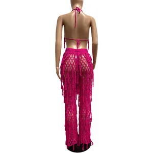 Vue arrière d'un ensemble de plage sexy en crochet rose vif avec pantalon à franges et glands