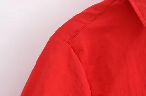 Gros plan détaillé de la couture d'épaule sur une chemise rouge ajustée pour femme.