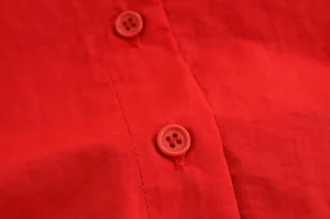 Détail macro des boutons de chemise rouges et de la texture du tissu pour femmes
