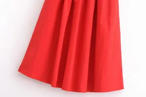 Vue détaillée de l'ourlet de la jupe plissée rouge montrant la texture lisse du tissu.