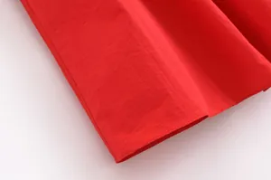 Vue détaillée du tissu rouge vif et des coutures nettes de l'ensemble jupe d'automne.