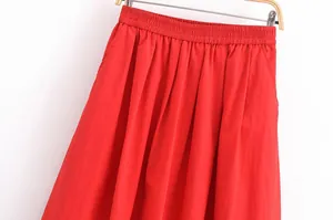 Détail d'une jupe midi plissée rouge vif montrant la taille élastiquée pour femme