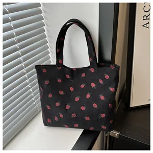 Japanese style black corduroy tote bag with cute strawberry print in a minimalist setting