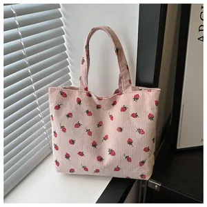 Detailed view of pink corduroy tote bag with cute red strawberry pattern print