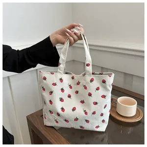 Close-up view of a cute strawberry print corduroy tote bag showing its soft fabric texture