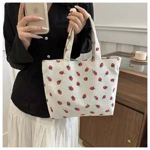 Close-up of a cream corduroy tote bag featuring a cute strawberry print pattern