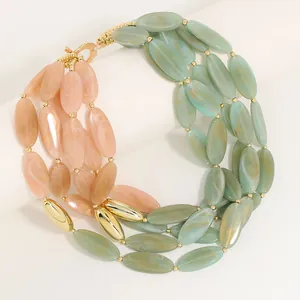 Detailansicht einer mehrreihigen Kette mit rosa und grünen ovalen Perlen und Goldakzenten