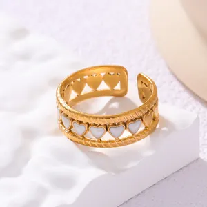 Close-up of gold-plated open ring with white enamel heart patterns