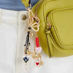 Detalle de colgantes de corazón y cámara de fotos en un bolso de color verde lima.