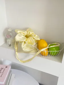 Detailed view of a yellow satin flower-shaped drawstring bag in a minimalist scene setup