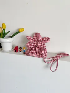 Close-up of the red and white gingham flower-shaped small crossbody bag with props