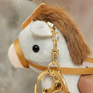 Macro detail of plush horse keychain with gold-tone metal hardware and brown mane