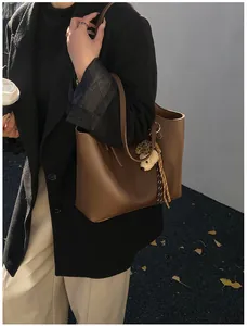 Detailed view of a vintage brown leather tote bag worn by a model in black blazer.