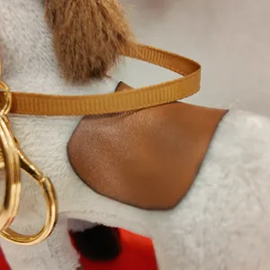 Macro view of brown leather saddle and soft white fur on horse plush keychain charm