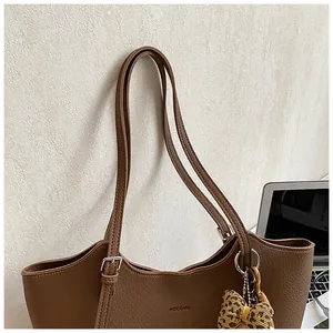 Close-up of a vintage brown leather tote bag with a leopard print bow charm accessory
