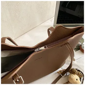 Close-up of brown pebble leather tote bag with top zipper and inner lining detail