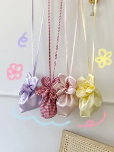 Four colorful cute flower-shaped crossbody bags in satin and gingham fabrics hanging.