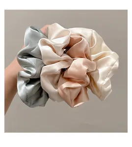 Detalle de coleteros de satén extragrandes en tonos pastel elegantes para peinados con estilo.