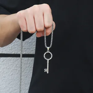 Détail en gros plan d'un pendentif clé en acier inoxydable argenté avec chiffres romains tenu