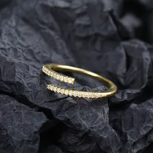 Gros plan sur une bague ouverte dorée ajustable ornée de pierres pavées scintillantes.