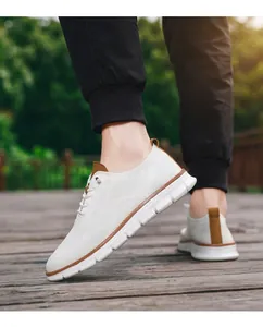 Close-up of white breathable mesh loafers with brown accents on a wooden deck.