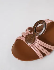 Close-up view of vintage wedge sandal vamp with pink straps and wooden buckle detail