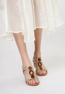 Elegant women's wedge sandals with wooden ring details and beige straps in a fashion shot