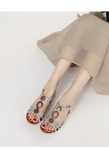 Close-up of retro silver wedge sandals with wooden ring accents worn by a model