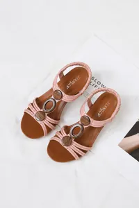 Detailed top-down view of pink women's Roman sandals with decorative wood rings on white