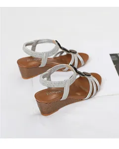Detail view of stylish silver wedge sandals with brown insole and wooden texture heel