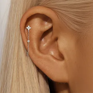 Close-up of a silver moissanite four-leaf tassel earring on a cartilage piercing.