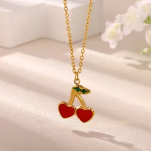 Close-up detail of a gold necklace featuring a red heart-shaped cherry pendant