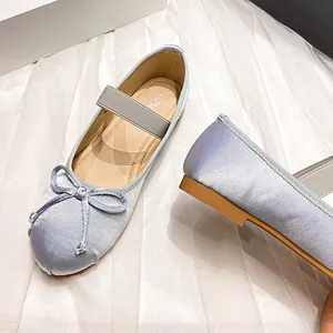 Elegant light blue satin ballet flats featuring a decorative bow and elastic Mary Jane strap