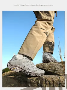 Gros plan de chaussures de randonnée grises marchant sur des rochers sous un ciel bleu