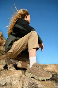 Gros plan détaillé de chaussures de randonnée kaki sur un terrain rocheux escarpé