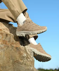 Gros plan de chaussures de randonnée kaki élégantes posées sur un rocher escarpé