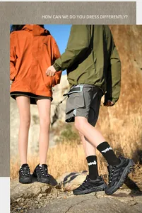 Couple portant des chaussures de randonnée noires sur un terrain montagneux au coucher du soleil.