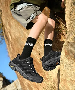 Gros plan des chaussures de randonnée noires portées lors de l'escalade d'un rocher.