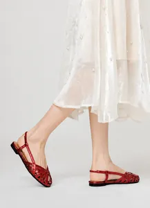 Detailansicht der glänzenden roten Metallic-Riemchen dieser eleganten flachen Sandalen.