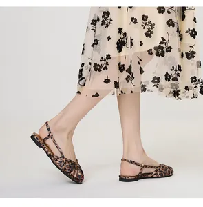 Detailansicht der flachen Sandalen mit Leopardenmuster und Kreuzriemen am Fuß