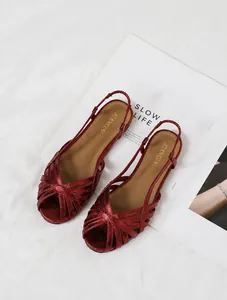 Draufsicht auf metallisch rote römische flache Sandalen mit Kreuzriemen und Riemen