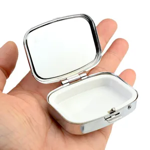Portable silver metal pill box with built-in mirror and compact white plastic interior